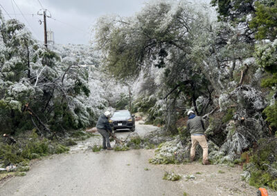 two workers remove limbs blocking a street after ice storm damage