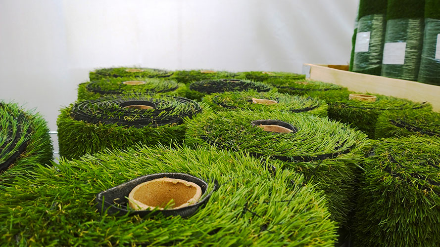 Rolls of artificial turf await installation. The plastic grass can be seen on the roll.